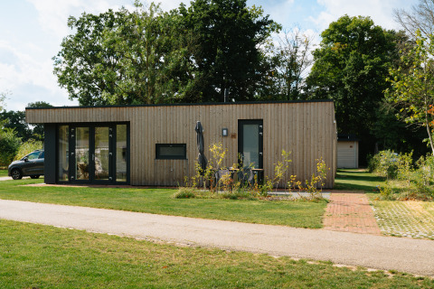 Moderne houten lodge bij Happy Oak Lodge, Holiday Park Mölke, Nederland, omgeven door natuur.