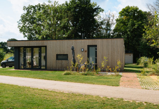 Moderne houten lodge bij Happy Oak Lodge, Holiday Park Mölke, Nederland, omgeven door natuur.