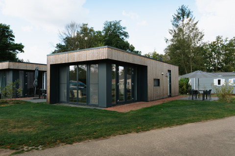 Moderne Happy Oak Lodge bij Holiday Park Mölke in Nederland met ruime terras en veel glas.