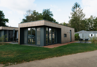 Moderne Happy Oak Lodge in Holiday Park Mölke in Nederland met grote ramen en aangrenzende tuin.