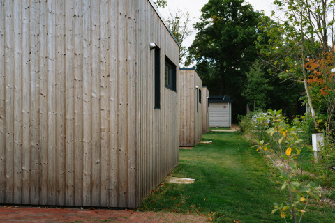 Houten chalets bij Happy Oak Lodge op Holiday Park Mölke in Nederland, gelegen aan gras en bomen.