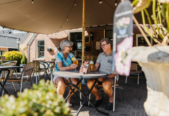 Deux personnes âgées savourent des boissons et discutent à une table extérieure dans un glamping.