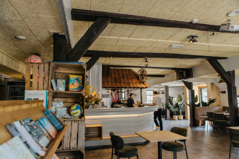 Interior acogedor de alojamiento glamping con sala, mostrador de bar, estanterías y plantas decorativas.