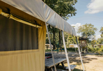 Tenda safari con parco giochi sullo sfondo al Recreation Park Den Blanken, Paesi Bassi, in una giornata soleggiata.