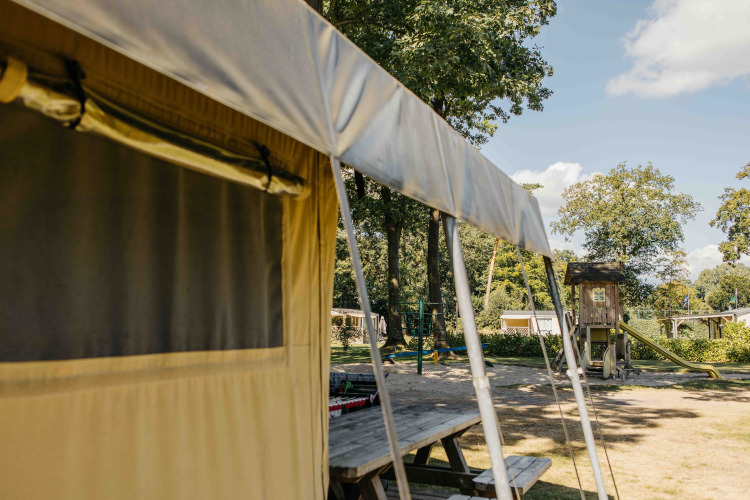 Tienda safari con parque infantil al fondo en Recreation Park Den Blanken, Países Bajos, un día soleado.