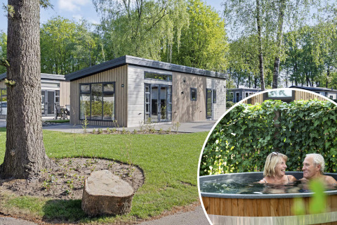 Nova Wellness-lodge met moderne houten gevel en tuin, ouder stel ontspant samen in de hottub buiten.