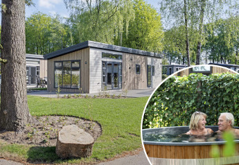 Lodge Nova Wellness dal design moderno con giardino, coppia anziana si rilassa nella vasca idromassaggio.