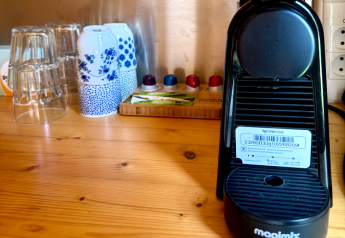 Eine Nahaufnahme einer Kaffeemaschine mit Tassen und Gläsern auf einem Holztisch in einer Hütte in Ieper, Belgien.