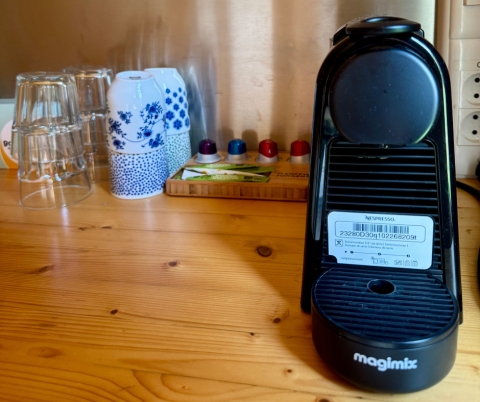 Cafetera con tazas y vasos en una mesa de madera dentro de una cabaña en Urban-Gardens Ieper, Bélgica.