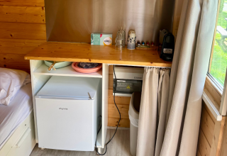 Køkkenhjørne i en hytte med et lille køleskab, kaffemaskine og træbord ved Urban-Gardens Ieper, Belgien.