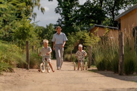 Een volwassene en twee kinderen spelen buiten bij de Sand Lodge in Holiday Park De IJsvogel, Nederland.