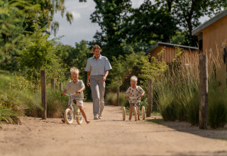An adult and two children play outside the Sand Lodge at Holiday Park De IJsvogel in the Netherlands.