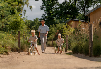 Een volwassene en twee kinderen spelen buiten bij de Sand Lodge in Holiday Park De IJsvogel, Nederland.