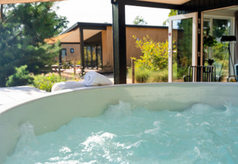 Bubbelbad bij Sand Lodge Jacuzzi op Vakantiepark De IJsvogel, Nederland, met uitzicht op de tuin.