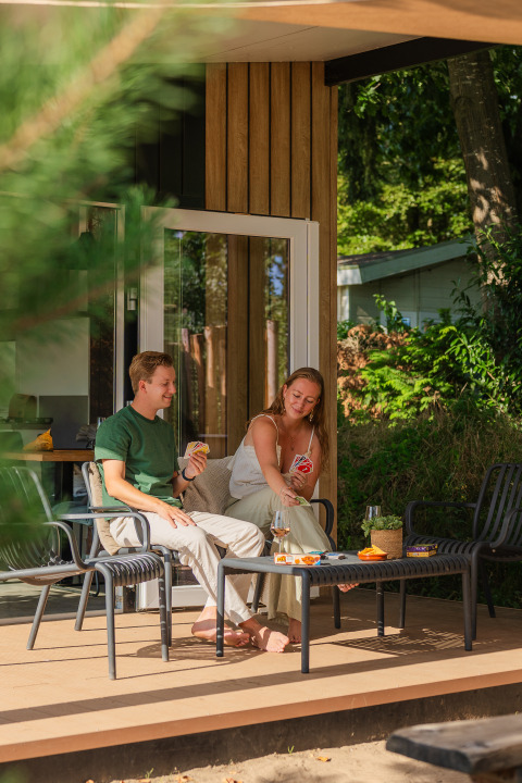 Deux personnes jouent aux cartes et se détendent sur la terrasse du Sand Lodge Jacuzzi à De IJsvogel.