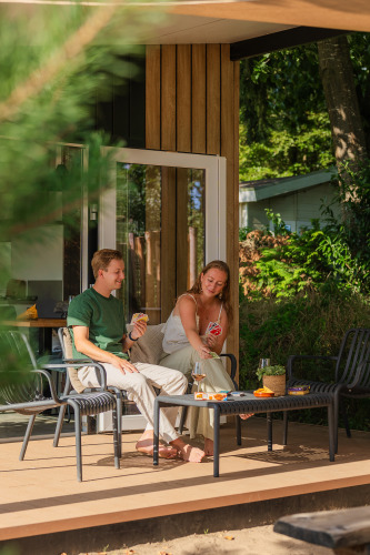 Zwei Personen spielen Karten und genießen die Sonne auf der Terrasse der Sand Lodge Jacuzzi in De IJsvogel.