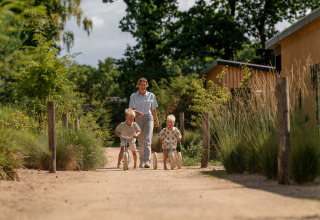 Erwachsener und zwei Kinder spielen auf einem Weg am Sand Lodge Jacuzzi im Holiday Park De IJsvogel, Niederlande.