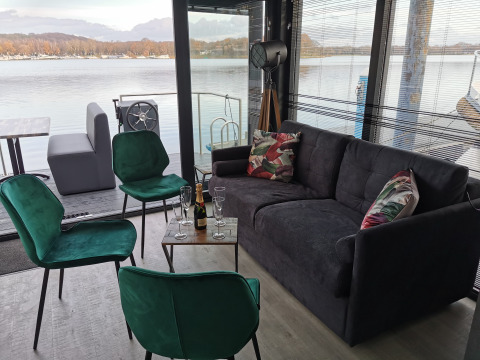 Salón moderno en una casa flotante en Marina Mookerplas, con vistas al lago y mobiliario elegante.