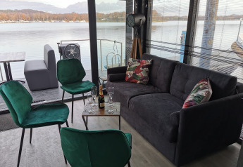 Salón moderno en una casa flotante en Marina Mookerplas, con vistas al lago y mobiliario elegante.