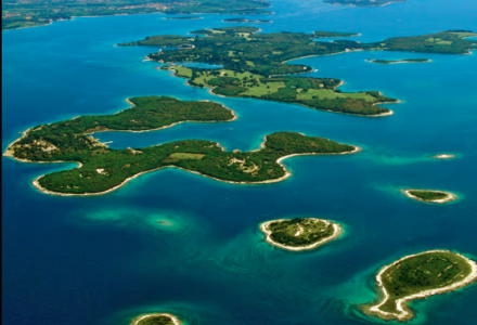 Luftfoto af smukke øer og klart blåt vand omkring Medulin i Istrien, Kroatien, med grøn natur.