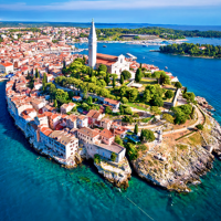 Luftfoto af en malerisk kystby nær Medulin, Istrien, Kroatien, hvor røde tage og klar blå hav ses tydeligt.