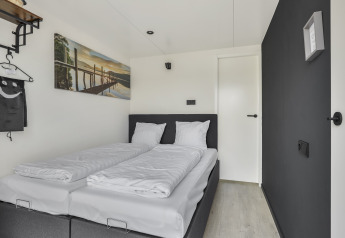 Dormitorio moderno en Houseboat Marina Mookerplas, Países Bajos, con cama doble y cuadro en la pared.