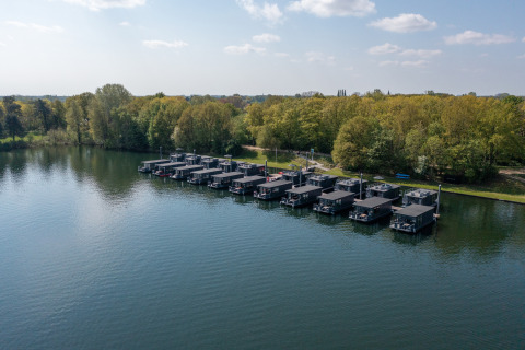 Hausboote mit Whirlpools am Steg der Marina Mookerplas in den Niederlanden, umgeben von Bäumen.