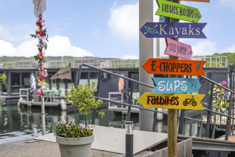 Cartel colorido en Houseboat Marina Mookerplas, Países Bajos, que muestra opciones como kayaks y fatbikes.