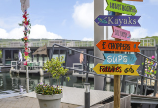 Cartel colorido en Houseboat Marina Mookerplas, Países Bajos, que muestra opciones como kayaks y fatbikes.