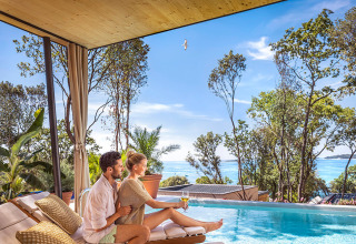 Couple se détend près de la piscine à Valamar Camping Istra, vue sur la mer et arbres, en Istrie, Croatie.
