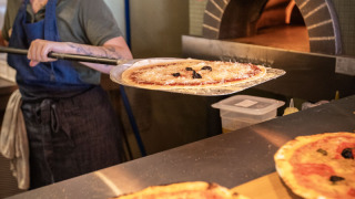 Une femme prépare une pizza au four à pierre au Huttopia Caminos de Galicia, un parc de vacances en Galice, Espagne.