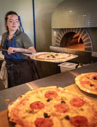 Une femme prépare une pizza au four à pierre au Huttopia Caminos de Galicia, un parc de vacances en Galice, Espagne.