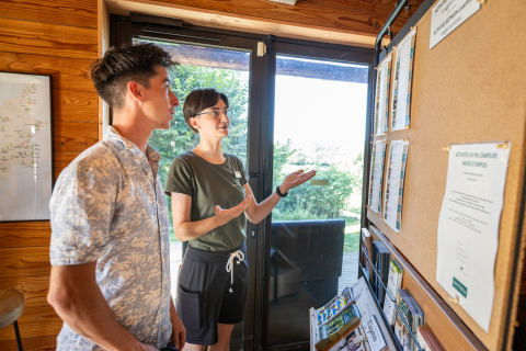 Two people reading an information board in the reception area at Huttopia Caminos de Galicia, Spain.