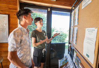 Two people reading an information board in the reception area at Huttopia Caminos de Galicia, Spain.
