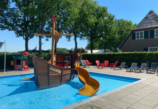 Buitenzwembad met piratenschip glijbaan en ligstoelen bij vakantiepark Duinhoeve in Noord-Brabant, Nederland.