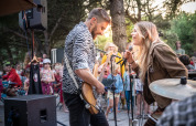 Twee muzikanten brengen live muziek voor een vrolijk publiek in een vakantiepark met glampingmogelijkheden.