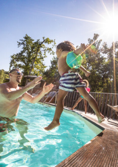 Un adulte attrape un enfant dans la piscine du Huttopia Caminos de Galicia, parc de vacances en Galice, Espagne.