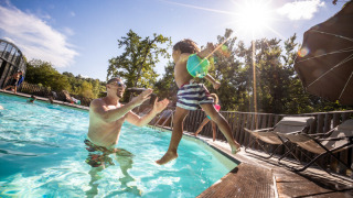 Un adulte attrape un enfant dans la piscine du Huttopia Caminos de Galicia, parc de vacances en Galice, Espagne.