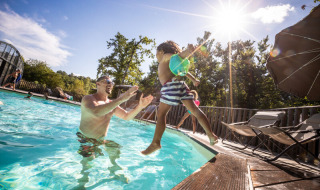 Un adulte attrape un enfant dans la piscine du Huttopia Caminos de Galicia, parc de vacances en Galice, Espagne.