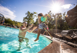 Un adulto atrapa a un niño en la piscina de Huttopia Caminos de Galicia, parque vacacional en Galicia, España.