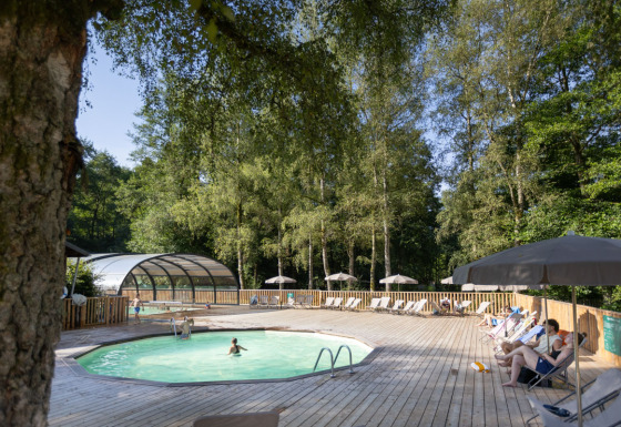 Piscina al aire libre rodeada de tumbonas y sombrillas en Huttopia Caminos de Galicia, Galicia, España.