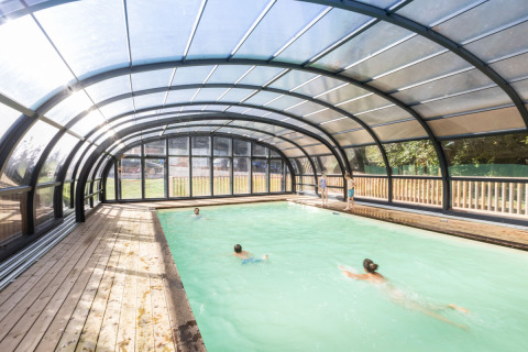 Overdækket swimmingpool med badende gæster på Huttopia Caminos de Galicia feriepark i Galicien, Spanien.