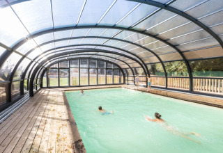 Covered swimming pool with people swimming at Huttopia Caminos de Galicia holiday park in Galicia, Spain.