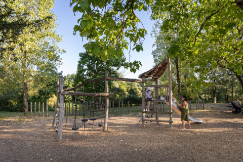 Parque infantil de madera rodeado de árboles en Huttopia Barcelona Pirineos, Cataluña, España.