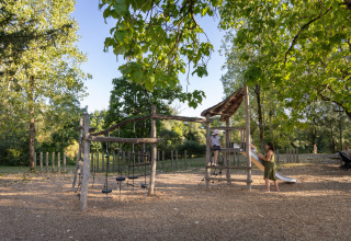 Houten speeltuin omgeven door bomen in Huttopia Barcelona Pirineos vakantiepark, Catalonië, Spanje.