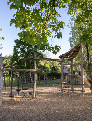 Holzspielplatz im Grünen im Huttopia Barcelona Pirineos Ferienpark in Katalonien, Spanien.