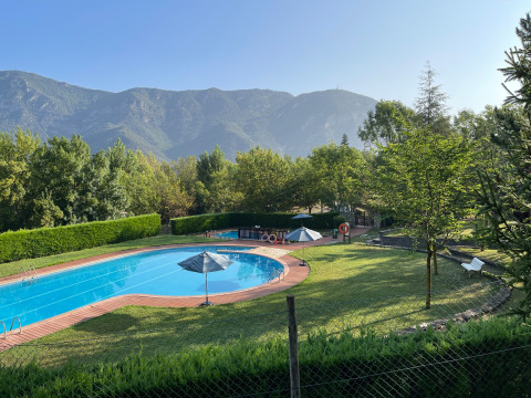 Piscina al aire libre y césped con sombrillas en Huttopia Barcelona Pirineos, Cataluña, España.