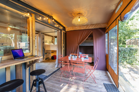 Hébergement glamping Arizona avec table à manger extérieure, ordinateur, meubles en bois et ambiance cosy.