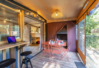 Glamping-indkvartering Arizona med udendørs spiseområde, laptop, træmøbler og hyggelig belysning.