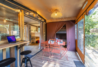 Alojamiento glamping Arizona con mesa de comedor exterior, portátil, muebles de madera y luces acogedoras.